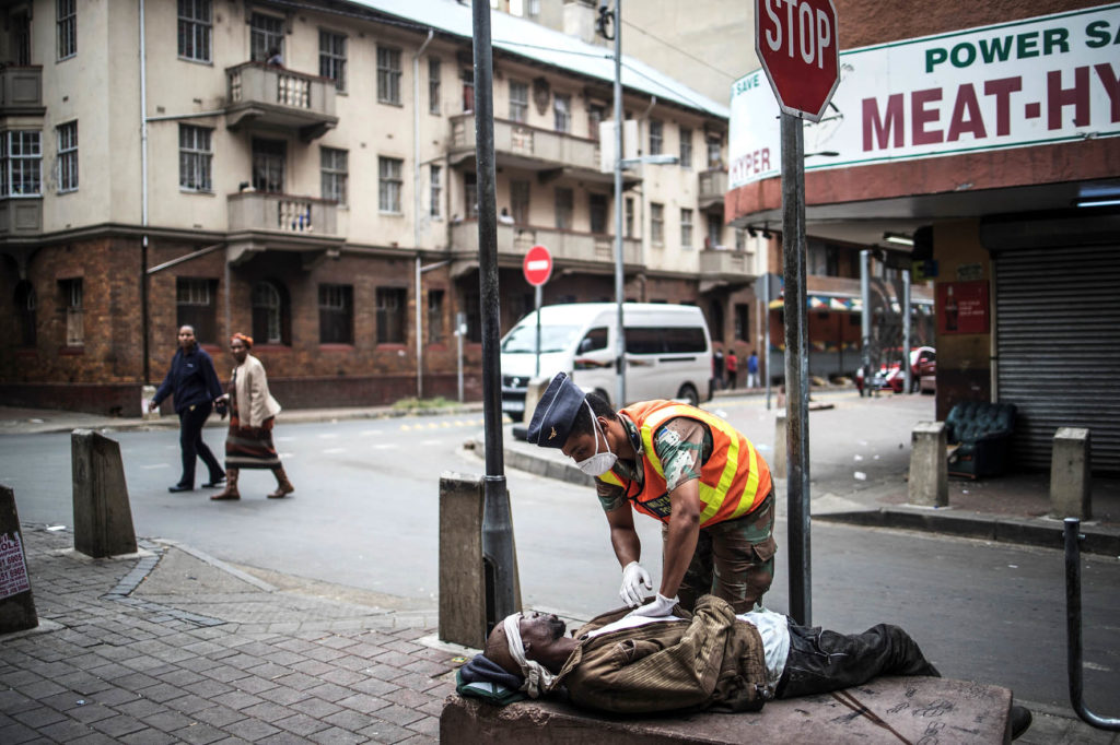 Johannesburg. Durante un pattugliamento nelle strade di Hillbrow un poliziotto della difesa nazionale (SANDF) controlla un senzatetto stremato da una overdose